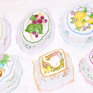 Peut inclure: Collection de six moules décoratifs en céramique blanche aux bords festonnés. Chaque moule présente un motif peint à la main différent, notamment des citrons, des framboises, un lapin et un bouquet de fleurs. Les moules sont parfaits pour la décoration.