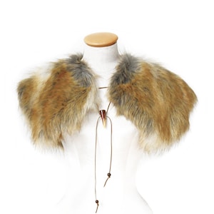 Könnte beinhalten: Ein Kunstfellkragen in Braun, Weiß und Grau. Der Kragen hat eine braune Lederschnur mit einem Knochenanhänger.