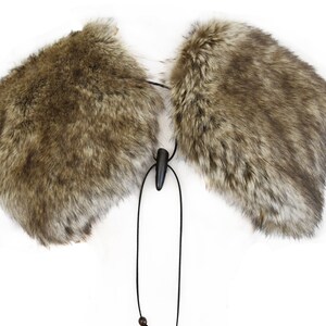 May include: A brown faux fur collar with a black cord and a wooden toggle. The collar is designed to be worn around the neck.