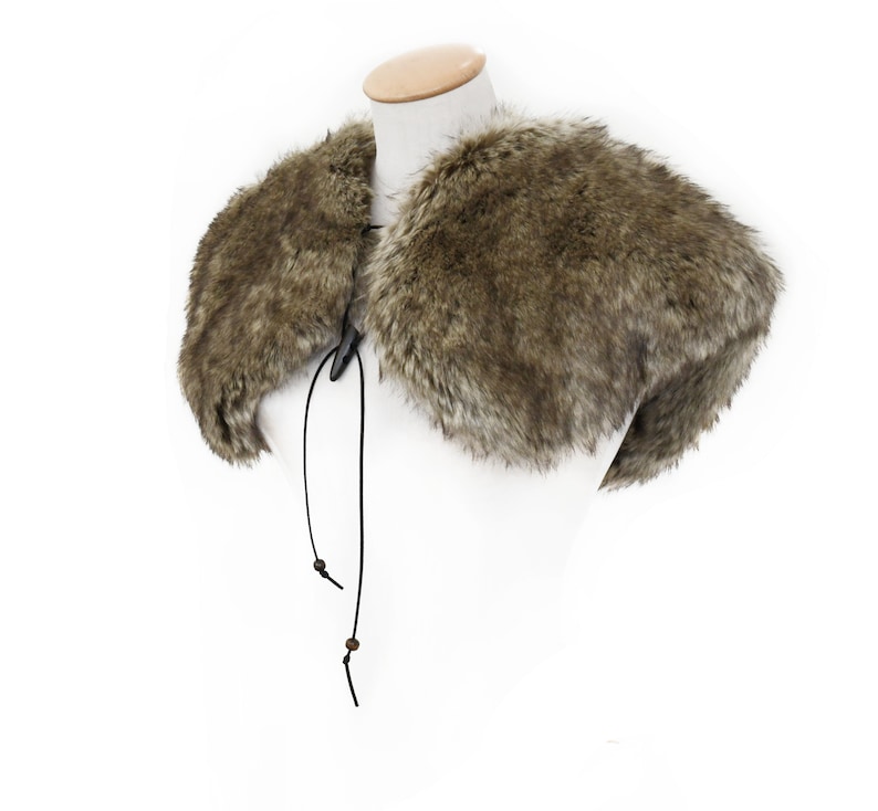 May include: A brown faux fur collar with a black leather tie closure. The collar is displayed on a white mannequin.