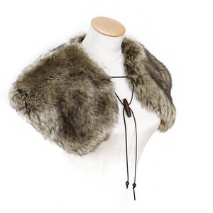 May include: A brown faux fur collar with a black leather tie and wooden beads. The collar is on a white mannequin.