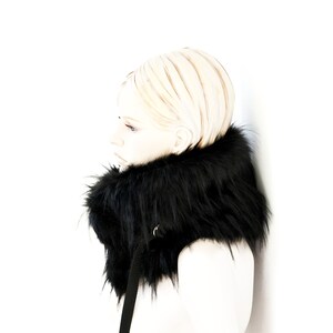 May include: A black faux fur collar with a black strap. The collar is worn by a mannequin with blonde hair.