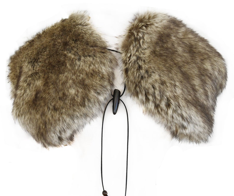 May include: A brown faux fur collar with a black cord and a wooden toggle. The collar is designed to be worn around the neck.