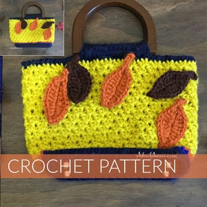 Może przedstawiać: Wzór na szydełku na żółtą torbę z brązowymi i pomarańczowymi akcentami liści. Torba ma drewniany uchwyt i niebieską lamówkę.