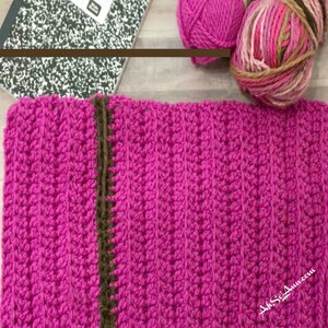 May include: A close-up of a pink crocheted fabric with a brown crocheted border. The fabric is textured and has a chevron pattern.
