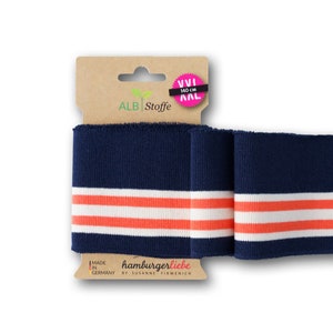 Könnte beinhalten: Marineblauer Strickbund mit zwei weißen und korallenfarbenen Streifen. Der Bund ist 140 cm lang und wird in Deutschland von hamburgerliebe by Susanne Firmenich hergestellt.