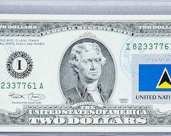 Peut inclure: Un billet de deux dollars avec un timbre de Sainte-Lucie représentant le drapeau du pays et le texte "NATIONS UNIES 22¢". Le billet présente également un portrait de Thomas Jefferson et le texte "I 82337761 A".