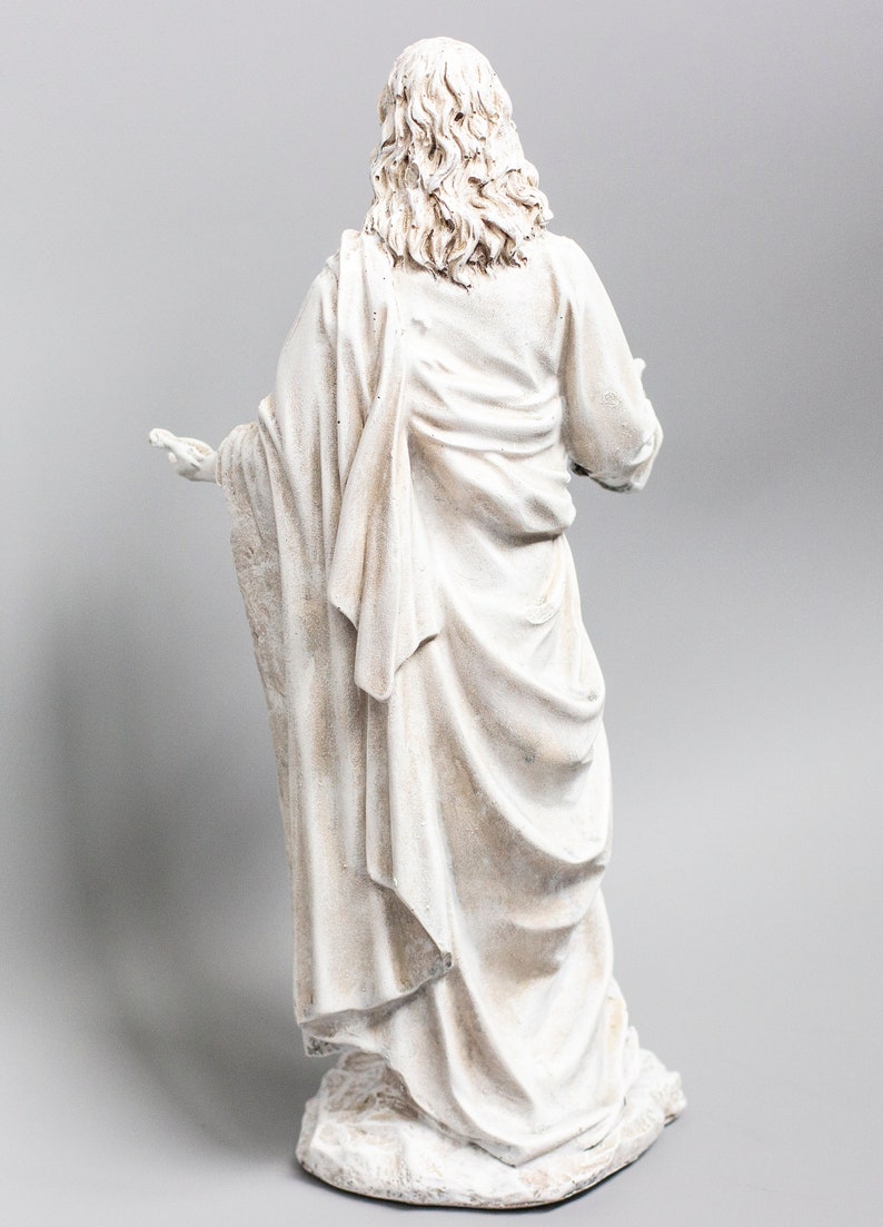 May include: White painted figurine of a person wearing a long robe with their back to the viewer. The figurine is standing on a base.