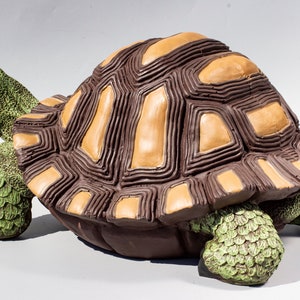 Pode incluir: Uma figura de tartaruga marrom e bege com uma casca detalhada e pernas e cabeça verdes.