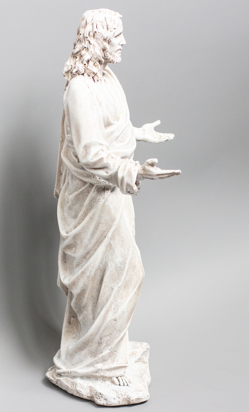 May include: White painted statue of Jesus with long hair and beard, wearing a robe, standing with arms outstretched.