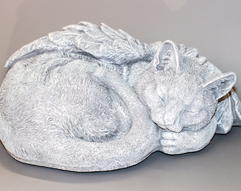 May include: A white ceramic sculpture of a sleeping cat with wings. The cat is curled up with its head resting on its paws. The wings are spread out behind the cat.