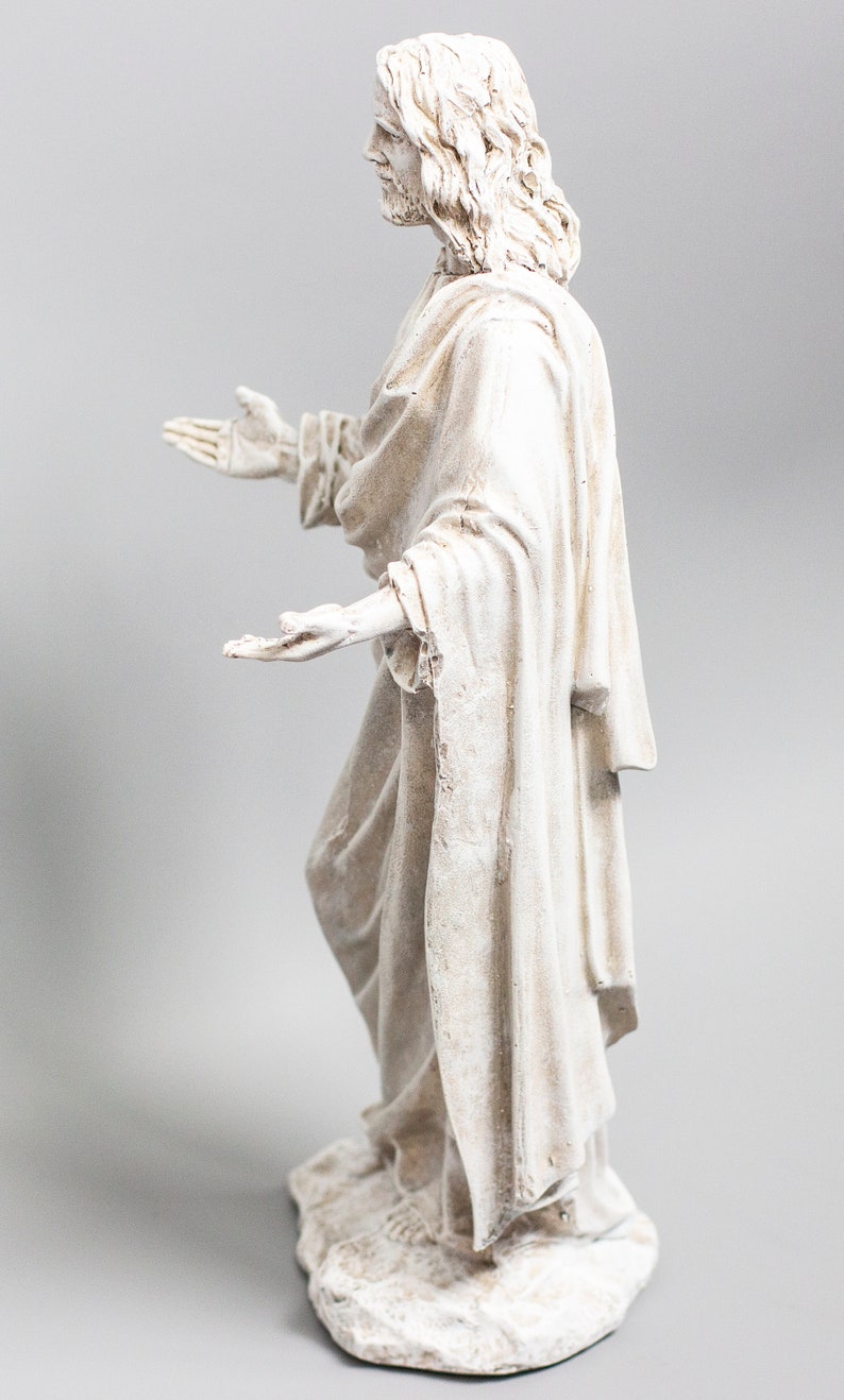 May include: White painted figurine of a person with long hair and a flowing robe, standing with arms outstretched.