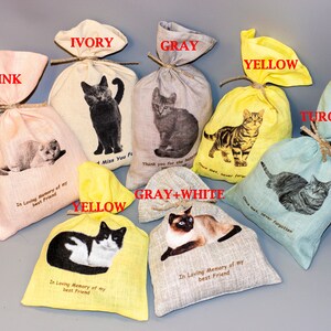 Puede incluir: Surtido de peque&ntilde;as bolsas de tela en varios colores, cada una con una imagen de gato diferente y un mensaje conmemorativo. Los colores incluyen rosa, marfil, gris, amarillo, turquesa y gris y blanco. Los mensajes incluyen "En memoria de mi mejor amigo", "Te extra&ntilde;o para siempre", "Gracias por el amor" y "Una vez conocido, nunca olvidado".