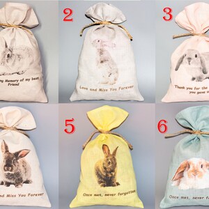 May include: Six small burlap bags with bunny rabbit images and text. The bags are in various colors, including beige, pink, yellow, and green. The text on the bags includes "In Loving Memory of my best Friend", "Love and Miss You Forever", "Thank you for the happiness you gave us", and "Once met, never forgotten".