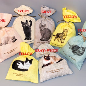 May include: Assortment of small fabric bags in various colors, each featuring a different cat image and a memorial message. The colors include pink, ivory, gray, yellow, turquoise, and gray and white. The messages include "In Loving Memory of my best friend", "I Miss You Forever", "Thank you for the love", and "Once met, never forgotten".