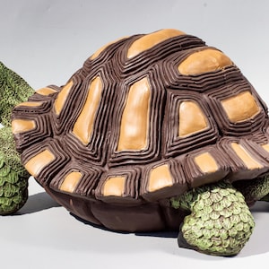 Pode incluir: Uma figura de tartaruga marrom e bege com uma casca detalhada e pernas e cabeça verdes.