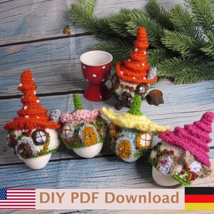 May include: Four crocheted egg covers shaped like miniature fairy houses with pointed roofs in orange, pink, yellow, and magenta, featuring small doors and windows, displayed alongside a red egg cup with white polka dots and a pine branch.