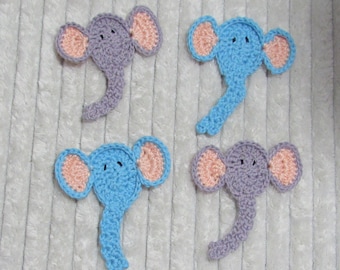Puede incluir: Cuatro aplicaciones de elefante de ganchillo, dos en azul claro y dos en morado claro, con orejas rosas. Los elefantes tienen una cara sonriente simple y una trompa enroscada.