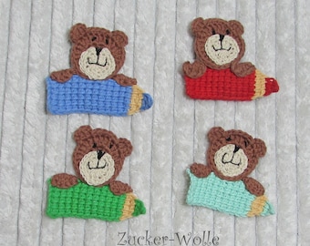 Puede incluir: Cuatro osos de peluche de crochet marrones sosteniendo lápices de diferentes colores: azul, rojo, verde y azul claro. Los lápices son de crochet y tienen una punta amarilla.