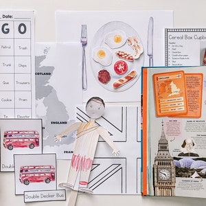 Op de afbeelding: Een verzameling educatief materiaal om over Engeland te leren, waaronder een bingokaart, een kaart van Engeland en Schotland, een papieren pop, een dubbeldekkerbus, een boek over Engeland en een ontbijtplaat met eieren, spek, worst en toast.