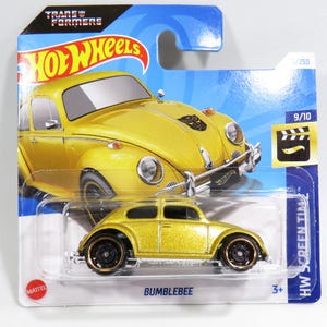 Pode incluir: Um carro de brinquedo amarelo Hot Wheels, um Volkswagen Beetle, com as palavras "Bumblebee" impressas na parte inferior do cartão. O carro faz parte da série Hot Wheels Screen Time, número 9/10.