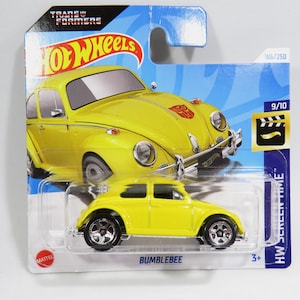 Puede incluir: Un coche de juguete amarillo Hot Wheels de Bumblebee de la franquicia Transformers. El coche es un Volkswagen Beetle con interior negro y ruedas negras. El coche está en una tarjeta azul y blanca con el logotipo de Hot Wheels y las palabras "Transformers" y "HW Screen Time".