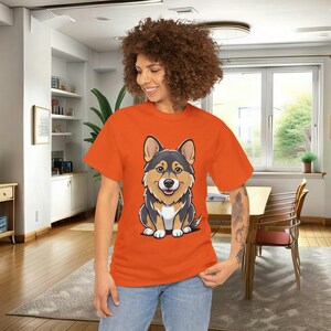 May include: Orange t-shirt featuring a cartoon illustration of a black and tan corgi. The corgi is sitting and looking directly at the viewer. The t-shirt is a comfortable, casual style, suitable for everyday wear.  The design is simple yet eye-catching, perfect for dog lovers and fans of cute animal illustrations.