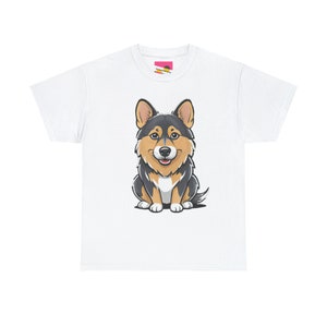 May include: A white t-shirt features a cartoon illustration of a corgi dog. The corgi is predominantly dark gray and black, with tan accents on its face and legs. It is sitting and looking directly at the viewer. The image is centered on the shirt. The shirt is a simple, short-sleeved crew neck style.