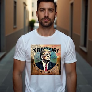 May include: A white t-shirt featuring a graphic print of a man with a red tie and the words "Traitor! To the U.S. Constitution" in a circle with an American flag background.