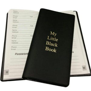 May include: Open black notebook with the text "My Little Black Book" in gold lettering. The notebook is open to reveal lined pages for names, addresses, phone numbers, and emails. The notebook is on a white background.