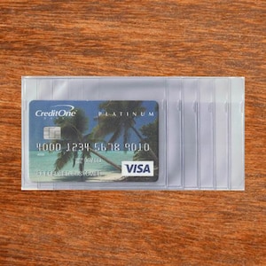 May include: A clear plastic card holder containing a CreditOne Platinum Visa card. The card features a tropical beach scene with palm trees and the Visa logo. The holder has multiple slots for organizing cards.