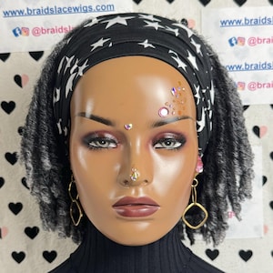 May include: A mannequin with short, gray and black dreadlocks wearing a black headband with white stars. The headband is tied in a knot at the back of the head. The mannequin is wearing a black turtleneck sweater and has rhinestones on the forehead.
