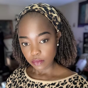 Peut inclure: Une femme avec des locs courts bruns porte un bandeau à imprimé léopard. Elle porte une chemise à imprimé léopard.