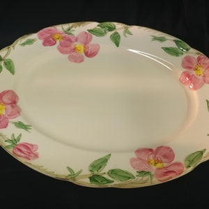 May include: A white oval serving platter with a scalloped edge and a floral design. The design features pink roses with yellow centers and green leaves.
