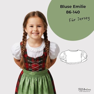May include: A sewing pattern for a blouse titled Bluse Emilie 86-140 Für Jersey, featuring a line drawing of a short-sleeved blouse with gathered shoulders and a round neckline, alongside the brand name TOSCAminni Schnittmanufaktur.