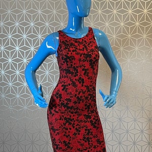 May include: A red sleeveless dress with a black floral print. The dress is fitted and has a scoop neck.