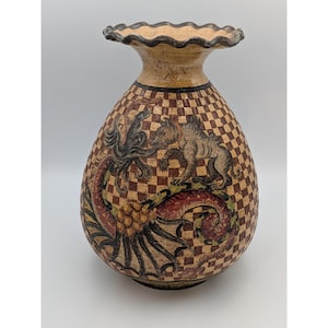 May include: A ceramic vase with a ruffled rim and a bulbous body featuring a brown and beige checkered pattern. The surface is decorated with a hand-painted illustration of a mythical creature with wings and a long tail in shades of red and black.