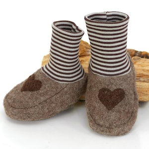 Könnte beinhalten: Ein Paar braune Filzpantoffeln mit braunen und weißen gestreiften Bündchen. Jeder Pantoffel hat ein braunes Filzherz an der Spitze.