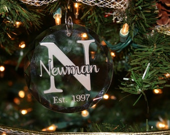 May include: A clear glass Christmas bauble with the letter N and the name Newman, along with the text "Est. 1997".