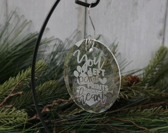 May include: A clear glass bauble with the text "You left paw prints on my heart" etched into it. The bauble is hanging from a silver hook.