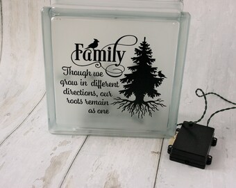May include: A glass block with a black silhouette of a tree and birds, with the text "Family Though we grow in different directions, our roots remain as one".