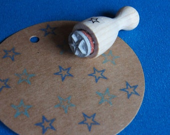 May include: A wooden stamp with a star design on a brown background with blue star prints.