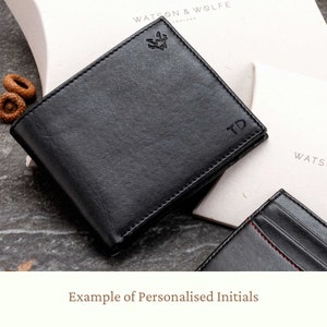 A black bifold coin purse wallet showing personalised initials. Embossed initials are positioned in the bottom right-hand corner.