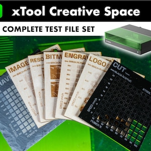 May include: A set of test files for a laser engraver, including a black acrylic sheet, birch plywood, and a slate tile. The files are labeled with the material type and the engraving settings. The files are arranged in a fan shape on a green surface. The text on the files reads: "IMAGE BIRCH PLYWOOD", "RESO BIRCH PLYWOOD", "BITM BIRCH PLYWOOD", "ENGRA BIRCH PLYWOOD", "LOGO BIRCH PLYWOOD", "CUT 3MM BLACK ACRYLIC", "ENGRAV SLATE".