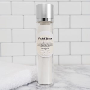 May include: A clear glass bottle with a silver lid and a white label that reads "Facial Serum". The label lists ingredients including aloe water, glycerin, magnesium, meadowfoam seed oil, vitamin E, magnesium, aloe leaf juice, vitamin C, panthenol, vitamin A, provitamin B5, and oil. The label also states "External Use Only" and "1.7 oz".