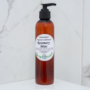 May include: A brown plastic bottle of Rosemary Mint natural conditioner with a black pump dispenser. The label reads "Handcrafted Natural Conditioner Rosemary Mint" with a list of ingredients and the shop's website.