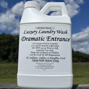 May include: A white plastic bottle of "Luxury Laundry Wash Dramatic Entrance" with a handle. The label includes usage instructions and the text "All Plant Based." The bottle is 64 oz.