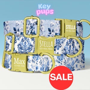 May include: Three dog collars with floral patterns in blue and white, featuring gold-colored buckles and rings. The collars are personalized with names and phone numbers. The word "SALE" is on a red circle in the foreground. The text "Key pups" is in the background.