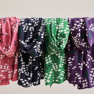 Pu&ograve; includere: Quattro sciarpe in tessuto con una stampa astratta bianca e verde. Le sciarpe sono in tonalit&agrave; rosa, blu scuro, verde e viola.