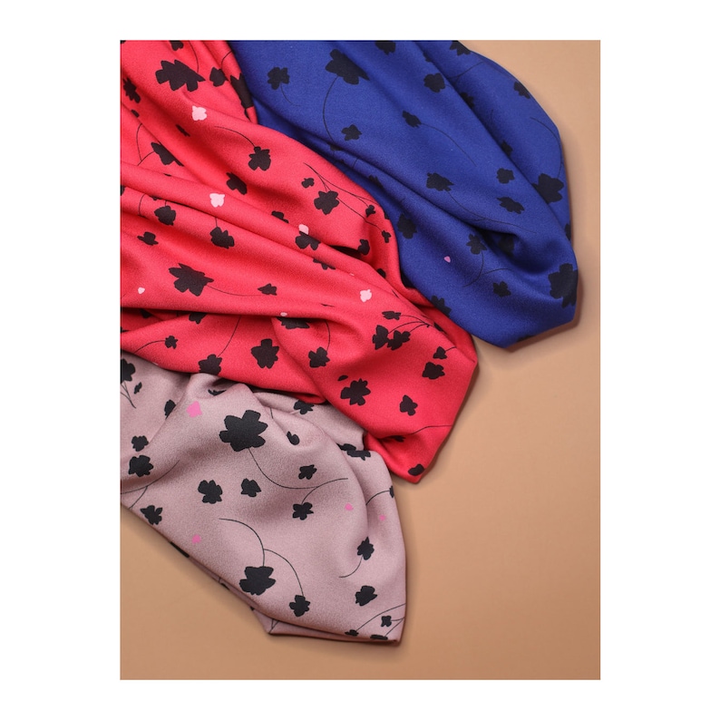 May include: Three fabric swatches with a floral pattern. The swatches are in shades of pink, blue, and gray. The flowers are black with pink centers.